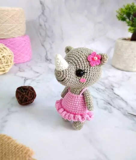 Little rhino amigurumi free crochet pattern featuring a small handmade rhinoceros with a pink dress and flower detail