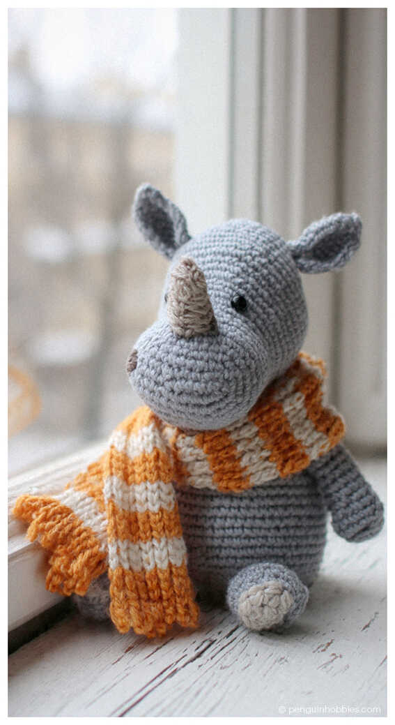 Cute rhino amigurumi crochet toy wearing a cozy striped scarf, a charming handmade plush animal perfect for nursery decor or a thoughtful baby gift