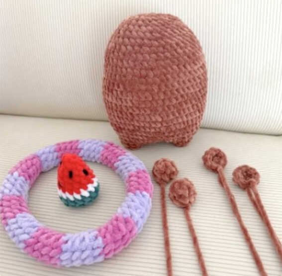 Capybara amigurumi free crochet pattern showing separate pieces including the body, swim ring, watermelon hat, and small limbs prepared for assembly