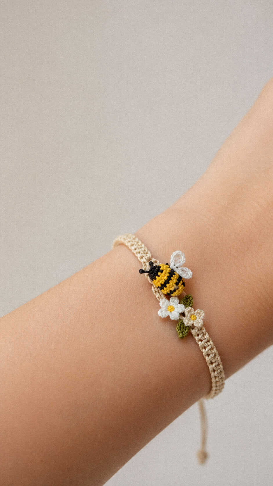 Tiny crochet bee bracelet with miniature flowers on a handmade adjustable wristband free pattern